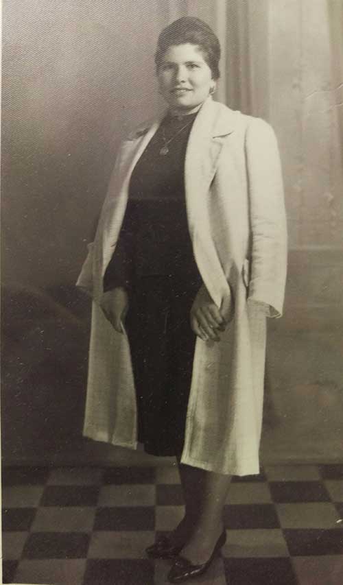 Une jeune femme portant une robe noire avec un manteau blanc.