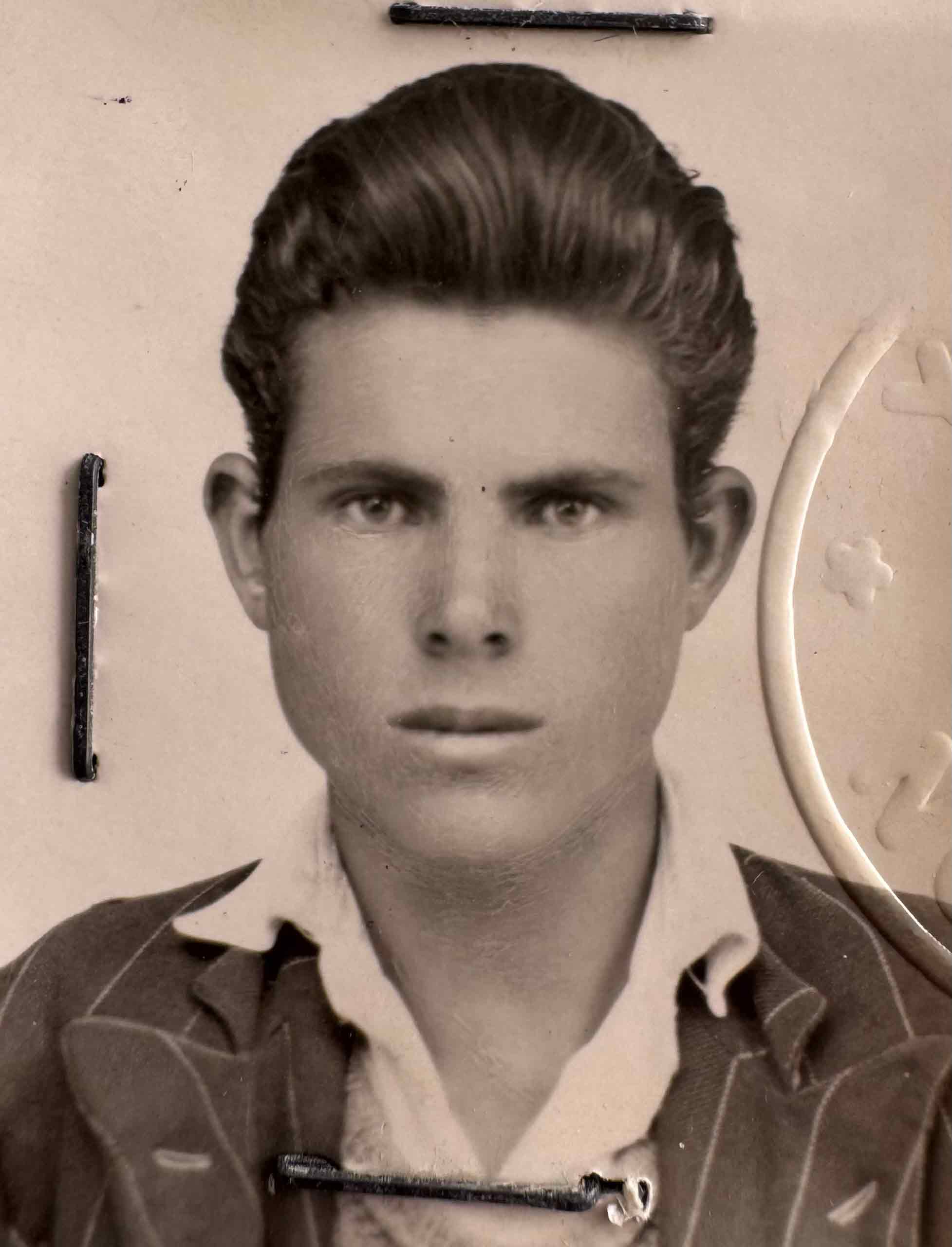 Photographie en noir et blanc de la photo du passeport grec d’un jeune homme.